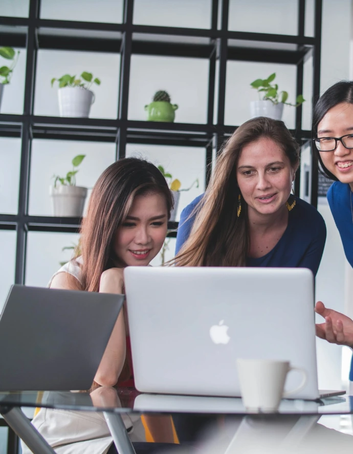 four people watching on white MacBook on top of glass-top table
